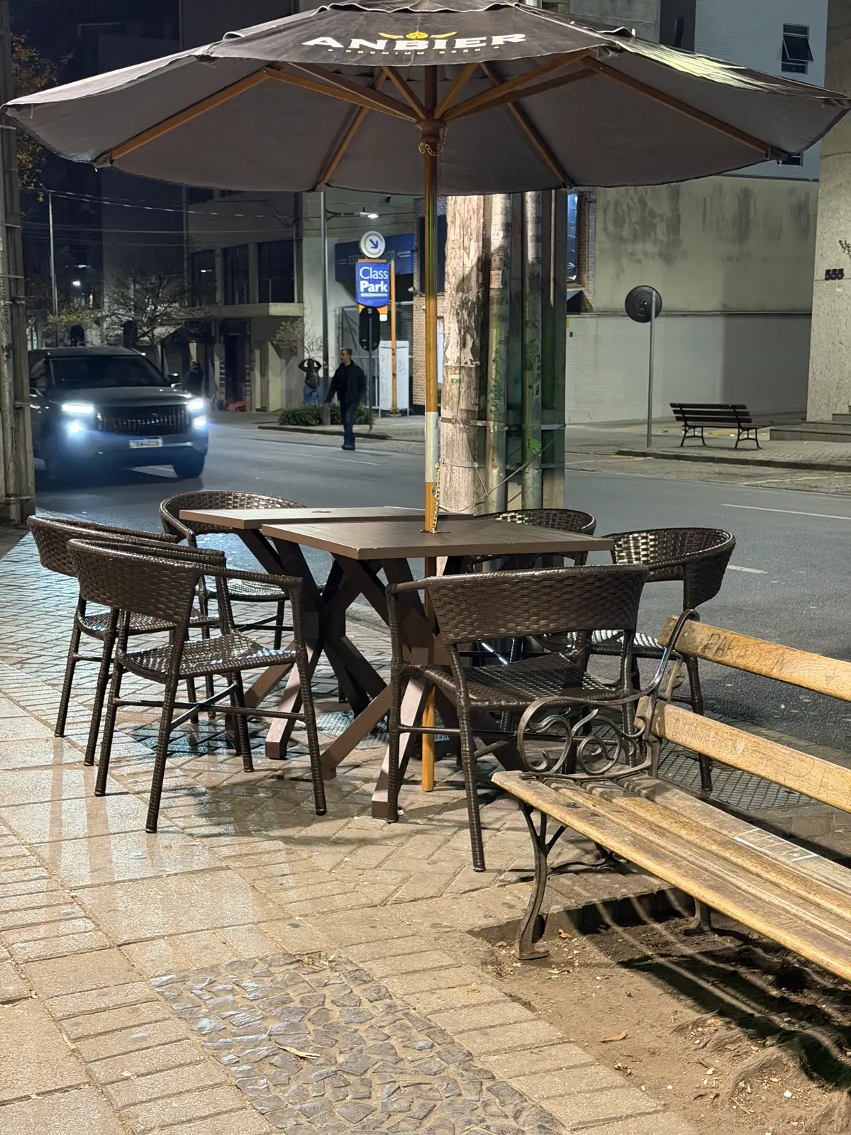 Pátio do bar com guarda-sol e banco à noite